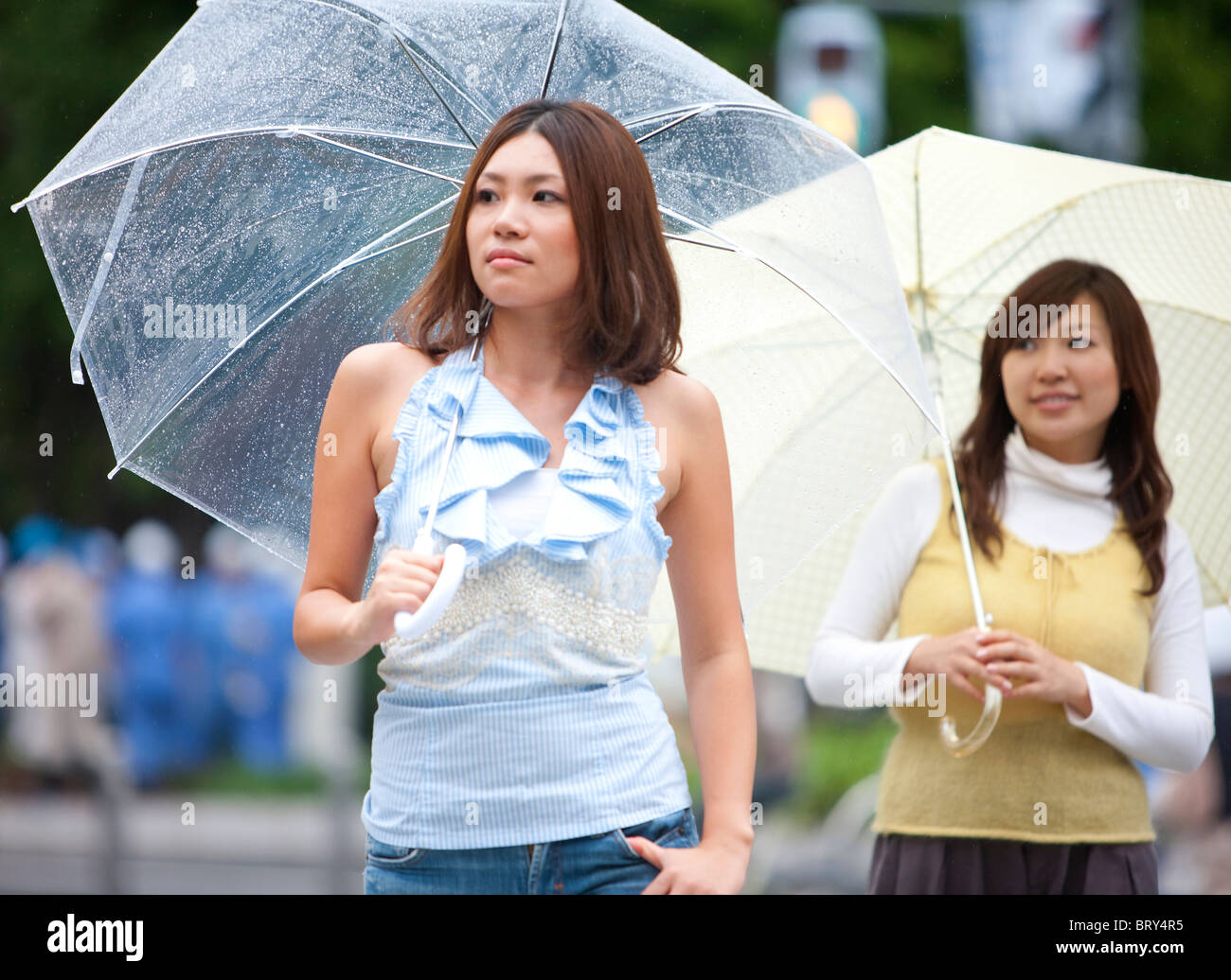 Two young women with umbrella walking down the street Stock Photo - Alamy