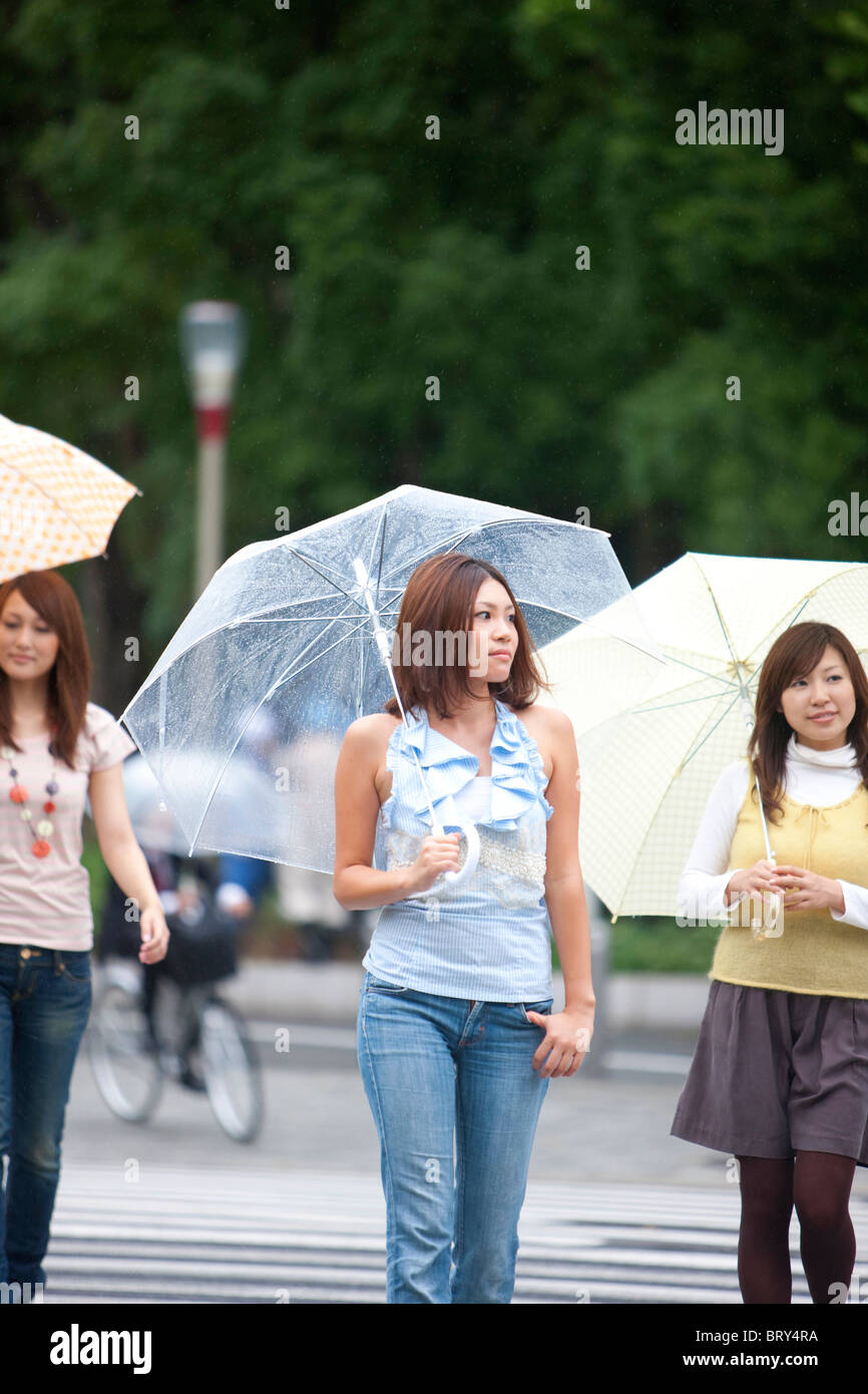 Three young women with umbrella crossing the street Stock Photo - Alamy