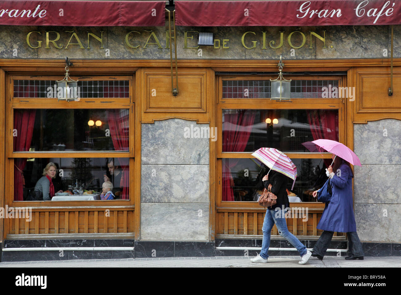 WOMEN WITH UMBRELLAS, EL CAFE GIJON, CAFE BAR FOR ARTISTS AND INTELLECTUALS OPENED IN 1888, PASEO DE RECOLETOS, MADRID, SPAIN Stock Photo