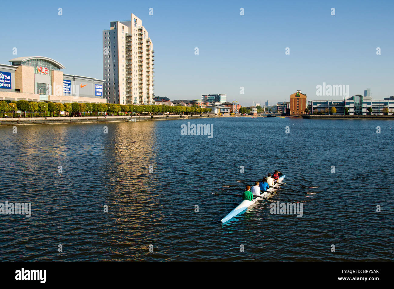 Two persons sculling (rowing) on the Manchester Ship Canal near the Lowry Outlet Mall,  Salford Quays, Manchester, UK Stock Photo