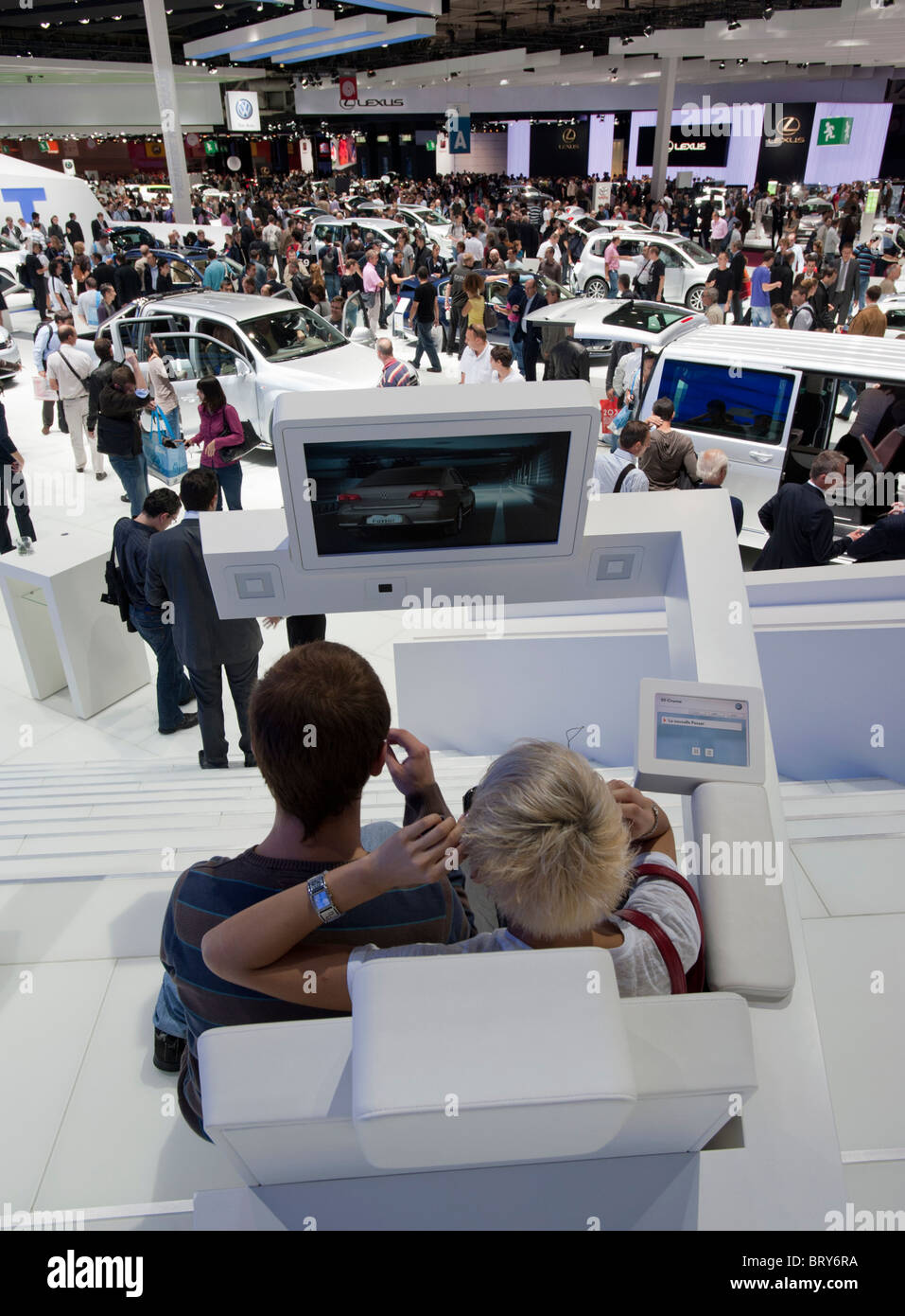 Visitors using 3D television  and view of busy hall at Paris Motor Show 2010 Stock Photo