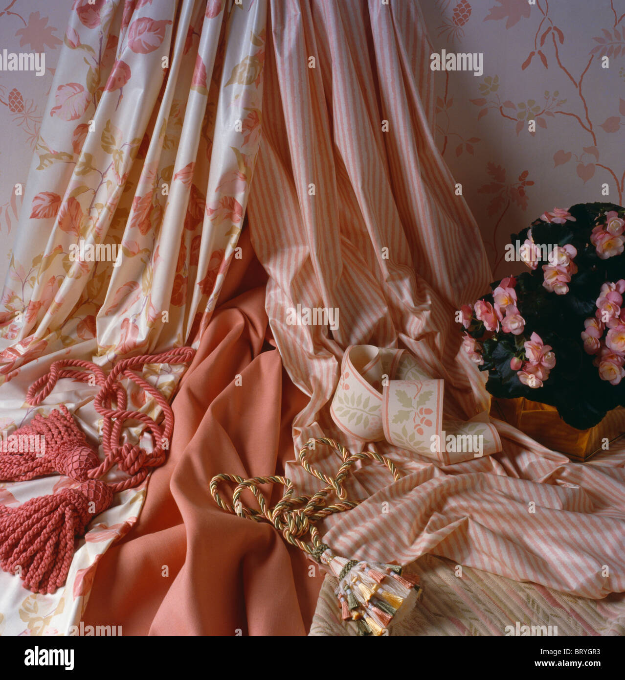 Close-up of pink floral and striped glazed cotton fabric with tassels and wallpaper borders Stock Photo