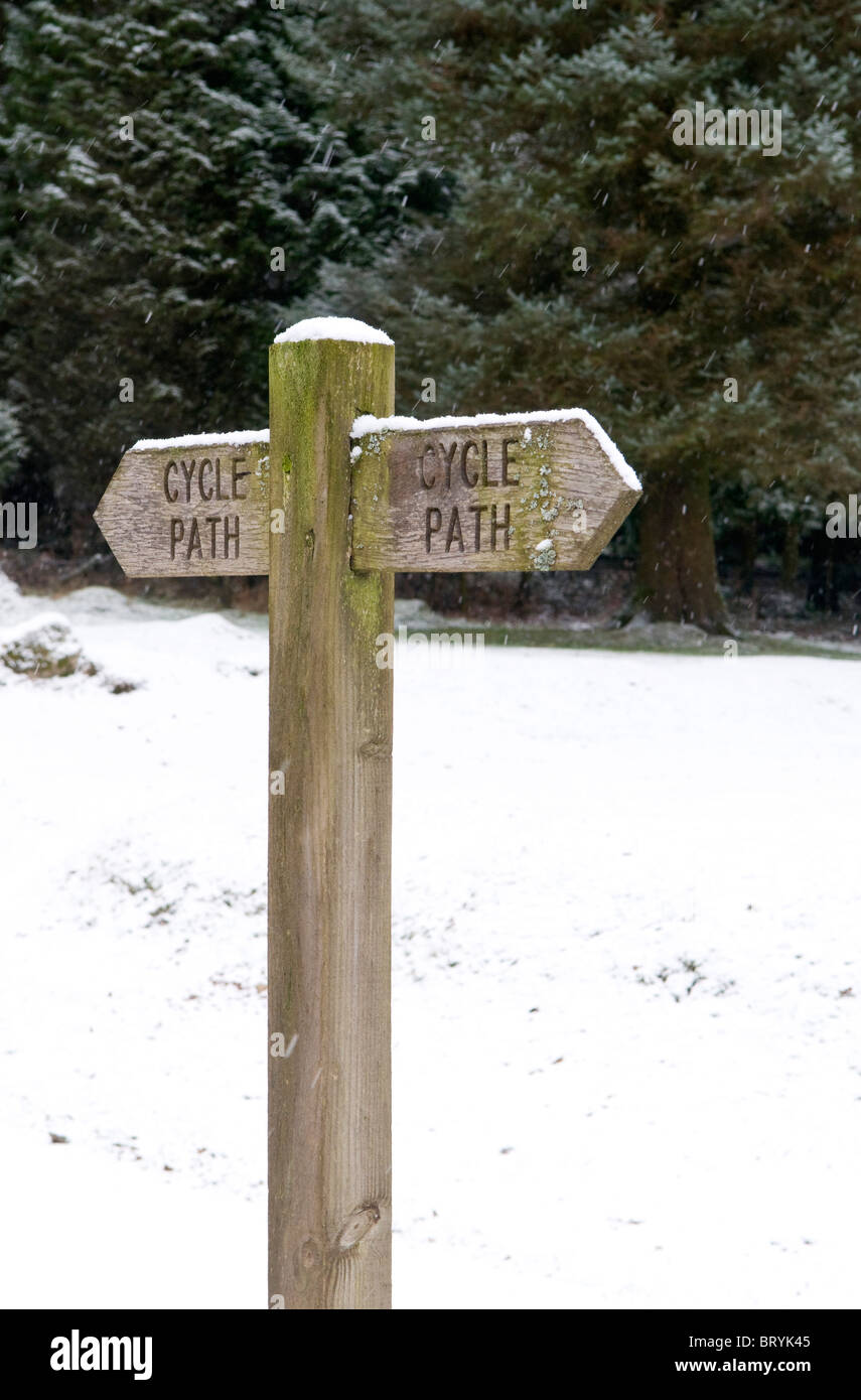 Wooden cycle path direction sign in snow, Dartmoor, Devon UK Stock
