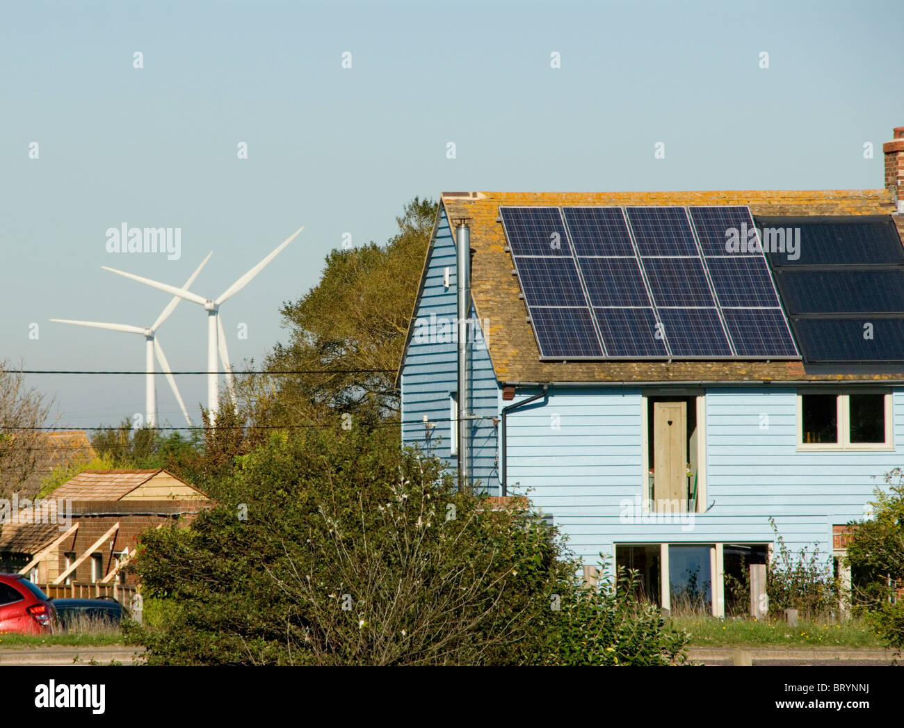 Wind turbines behind a house with solar panels The Recycled House Camber Rye east Sussex Stock Photo