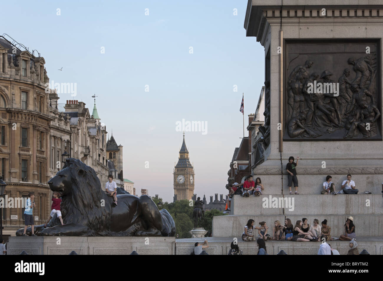 UK, ENGLAND, LONDON. Teenage tourist sitting at the base of Nelson's Column in Trafalgar Square. Big Ben clock tower in distance Stock Photo