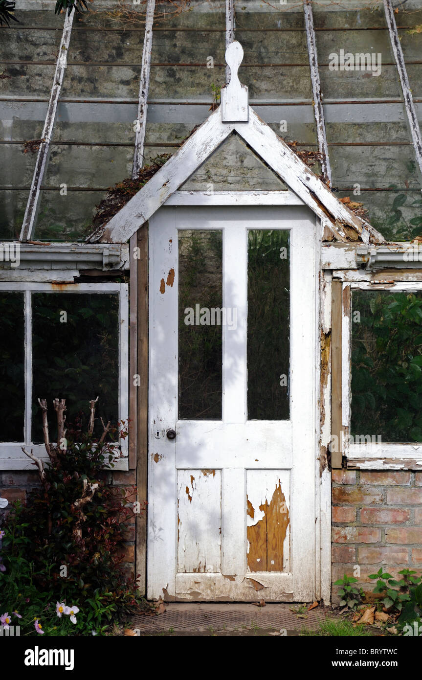 door of into an old decrepit victorian style greenhouse peeling paint disused disrepair Stock Photo