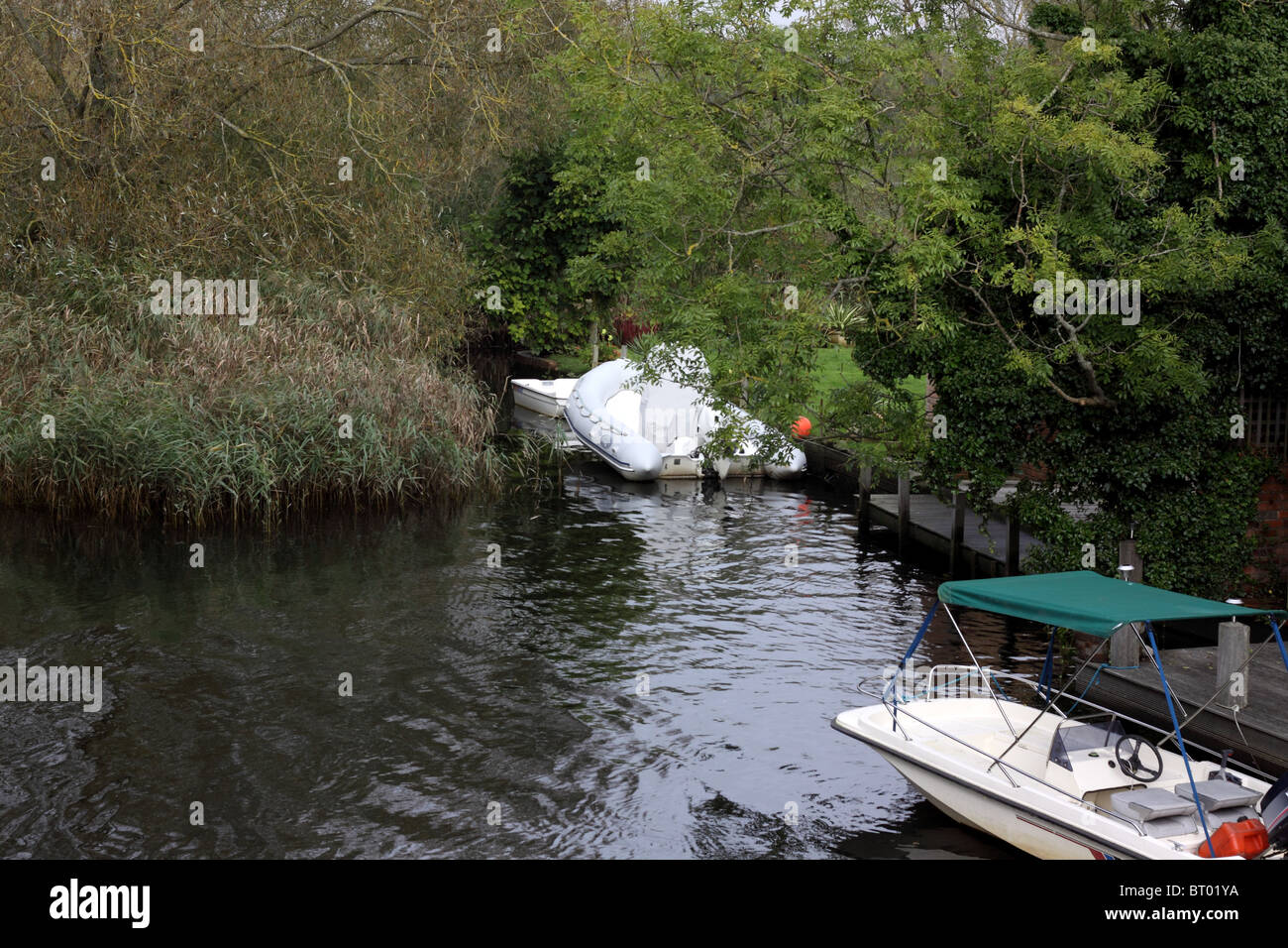 3 boats moored in a quiet backwater of  the River Avon, Christchurch, Dorset Stock Photo