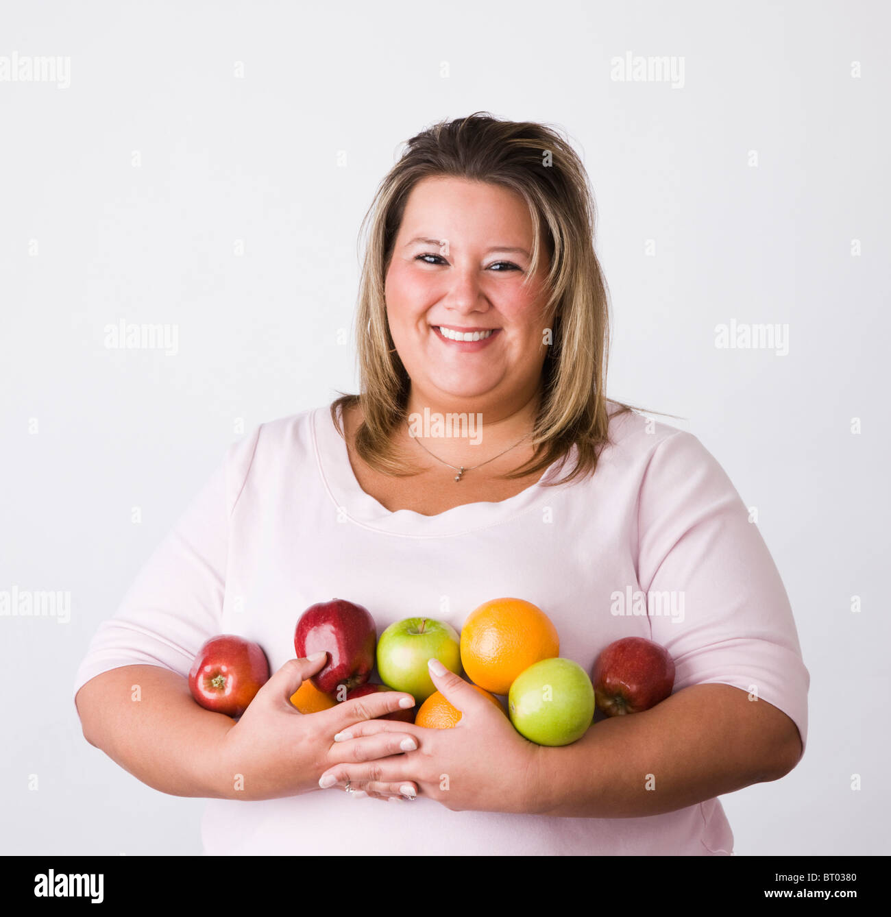 Portrait of smiling young woman holding fruits Stock Photo - Alamy