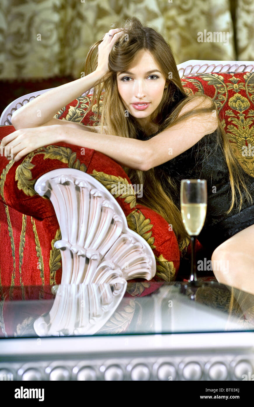 beautiful young rich woman near a coffee table with glass of fizz Stock Photo
