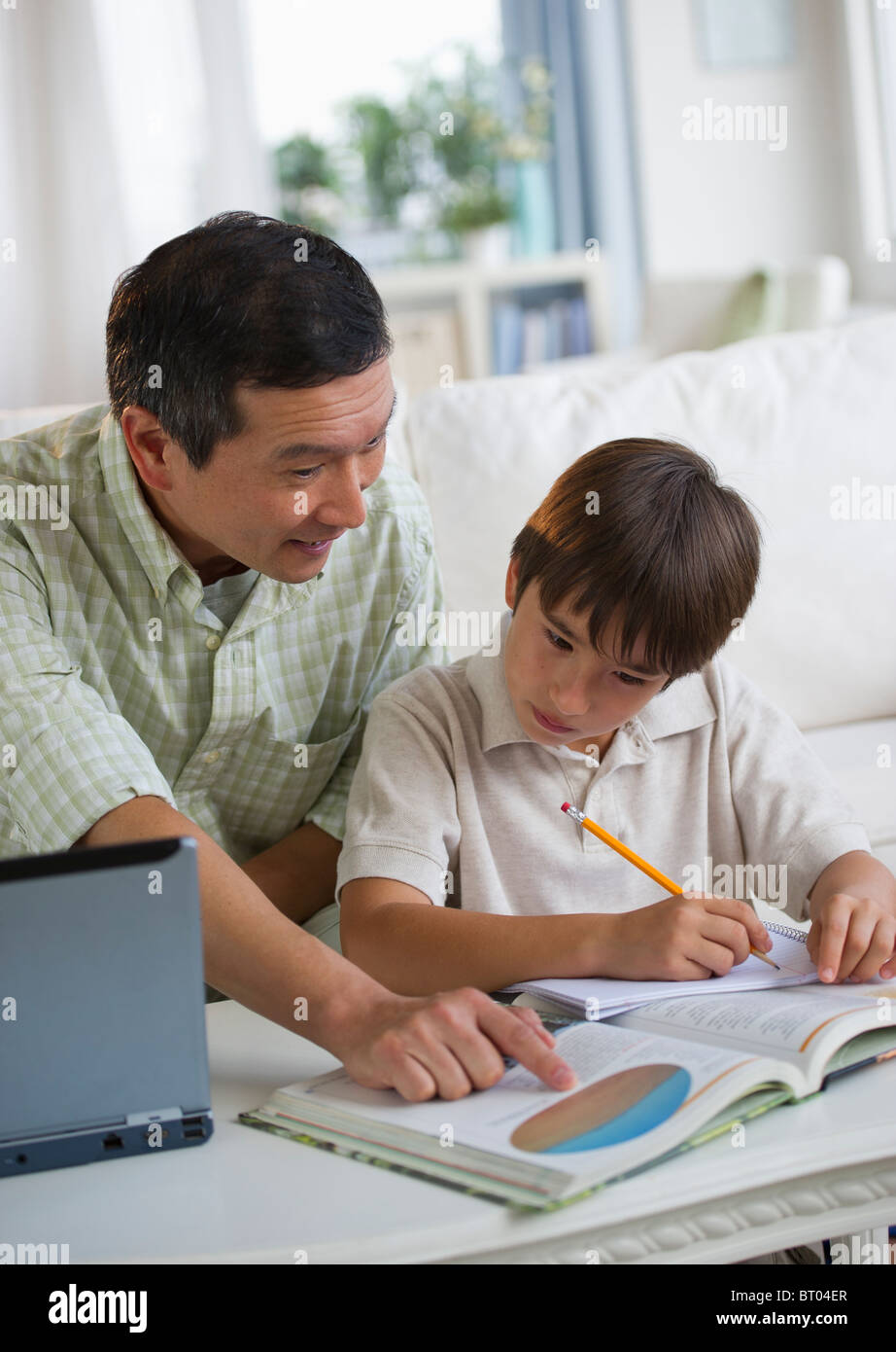 Father helping son with homework in living room Stock Photo - Alamy