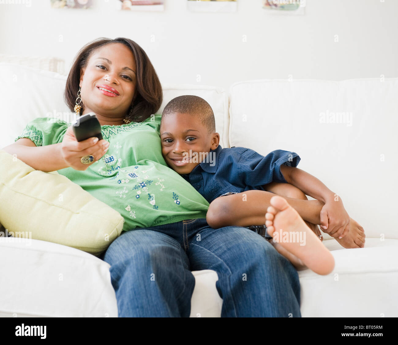 Black mother and son watching TV on living room sofa Stock Photo