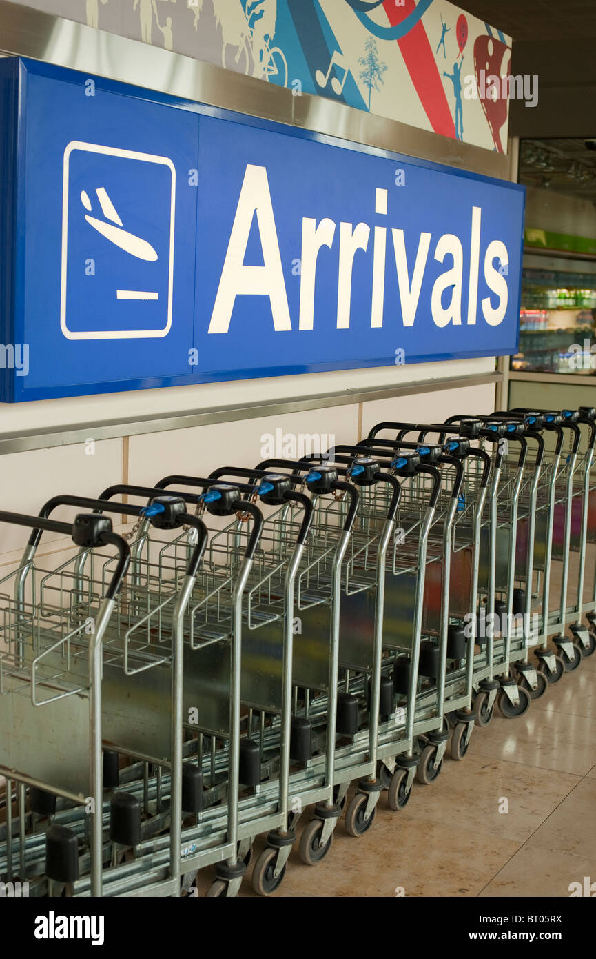 Airport Arrivals Hall Baggage Trolleys and Sign Stock Photo