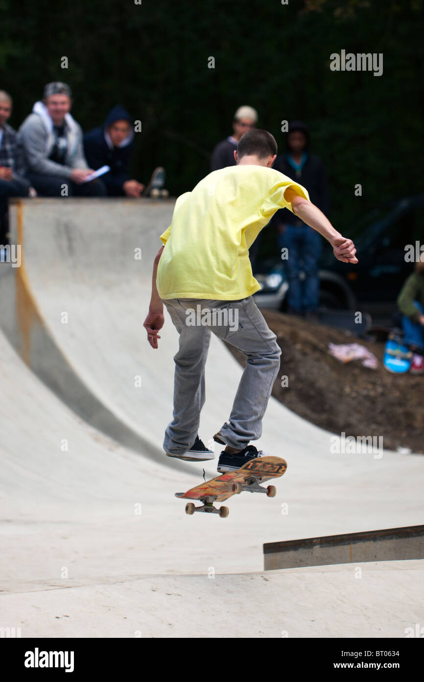 young skateboarder performing a jump, spectators in background Stock Photo