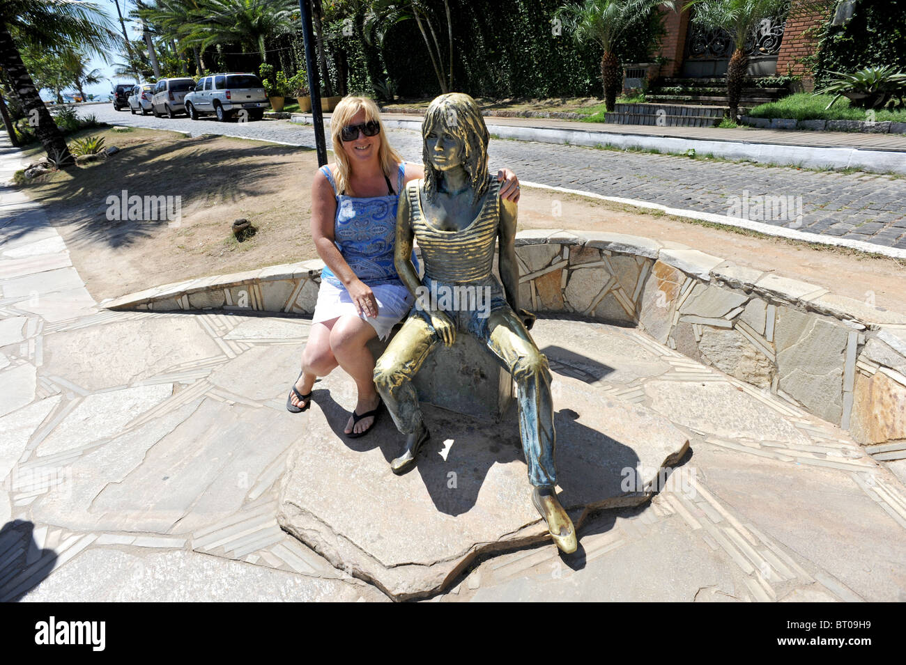 A tourist poses with the Brigitte Bardot statue in Buzios, she is credited with discovering Buzios in the 1960's Stock Photo