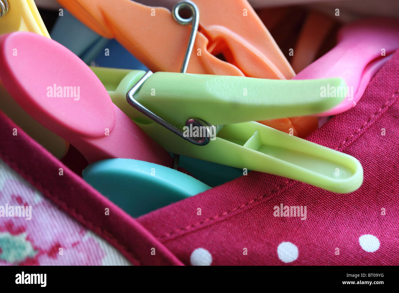Close up of multi-coloured plastic pegs in a peg bag Stock Photo