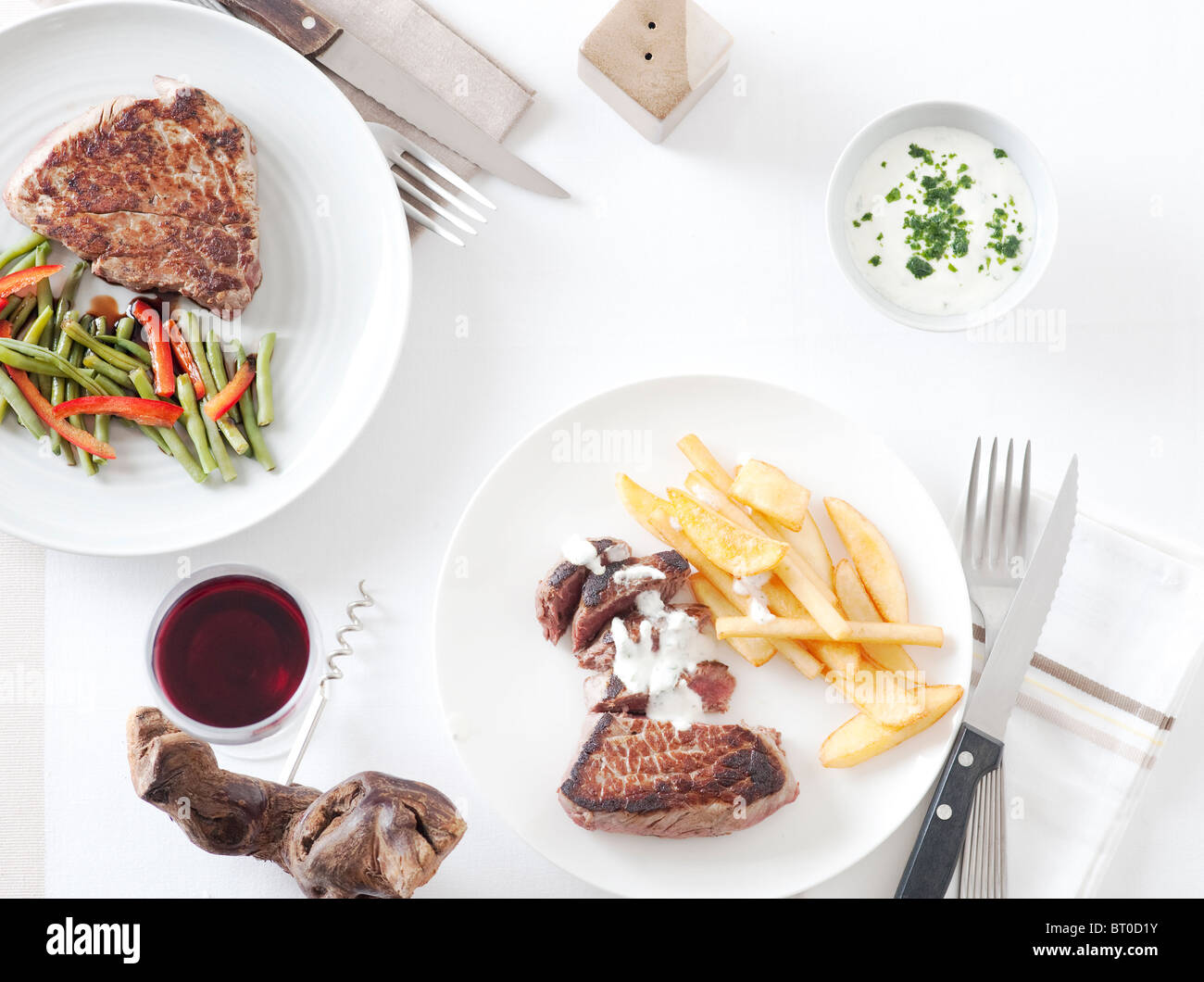 Table with  meat file, french fries, vegetables, a glass of wine Stock Photo