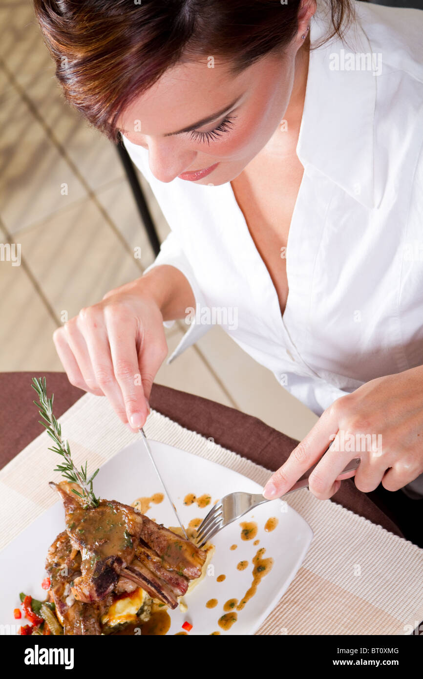 beautiful young woman eating steak in restaurant Stock Photo