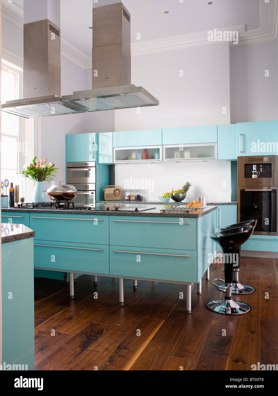 Double Extractors Above Island Unit In Modern White Kitchen With Pale Turquoise Fitted Units And Wooden Flooring Stock Photo Alamy