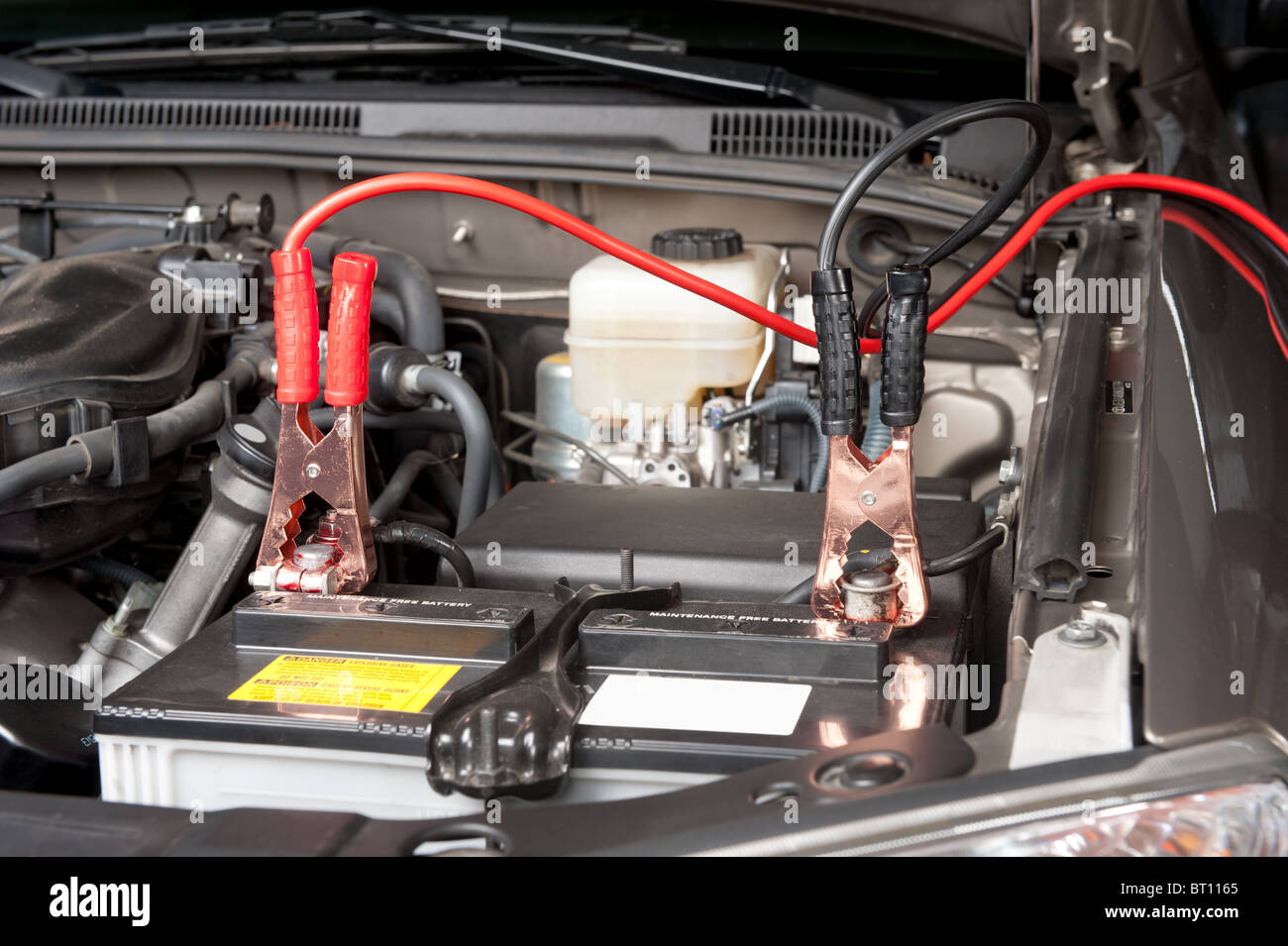 Battery charging cables transferring power to a dead battery. Stock Photo