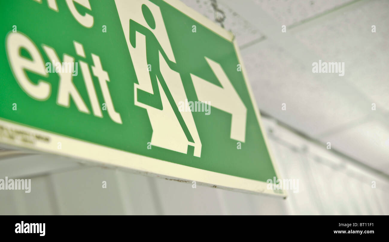 close up of green fire exit sign hanging from roof Stock Photo