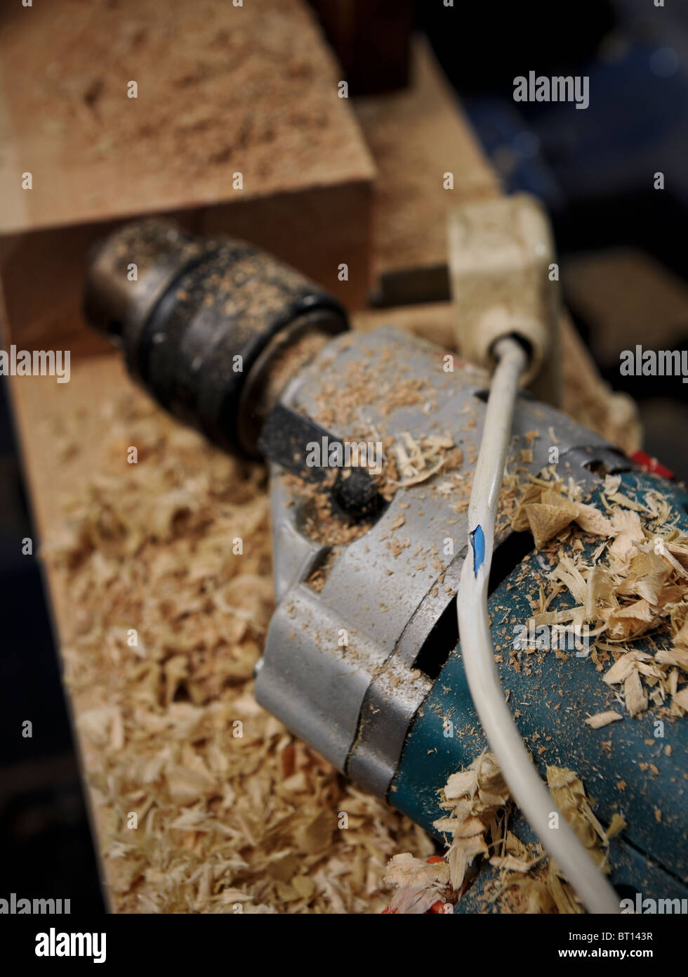 a dangerous fire risk with a split electrical plug cable on a drill surrounded with combustible materials on a work bench Stock Photo