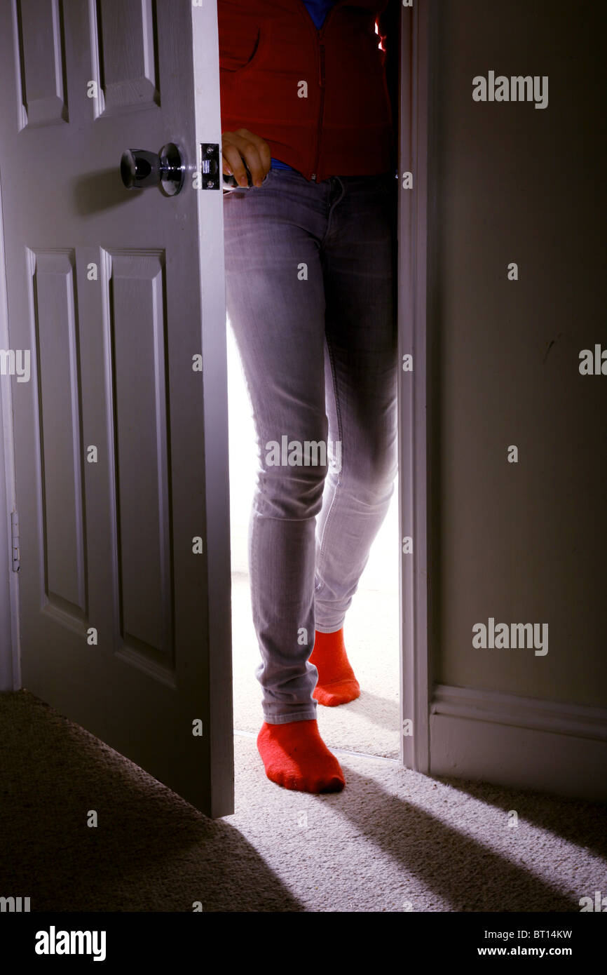 young girl wearing jeans and red socks walking into a dark room Stock Photo