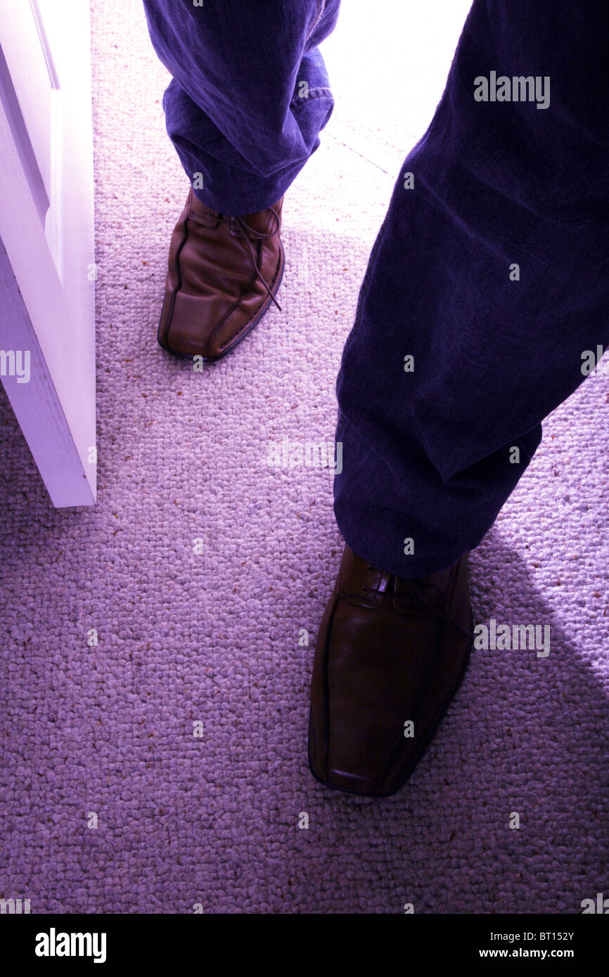 Man walks into a room wearing brown shoes and jeans. Stock Photo