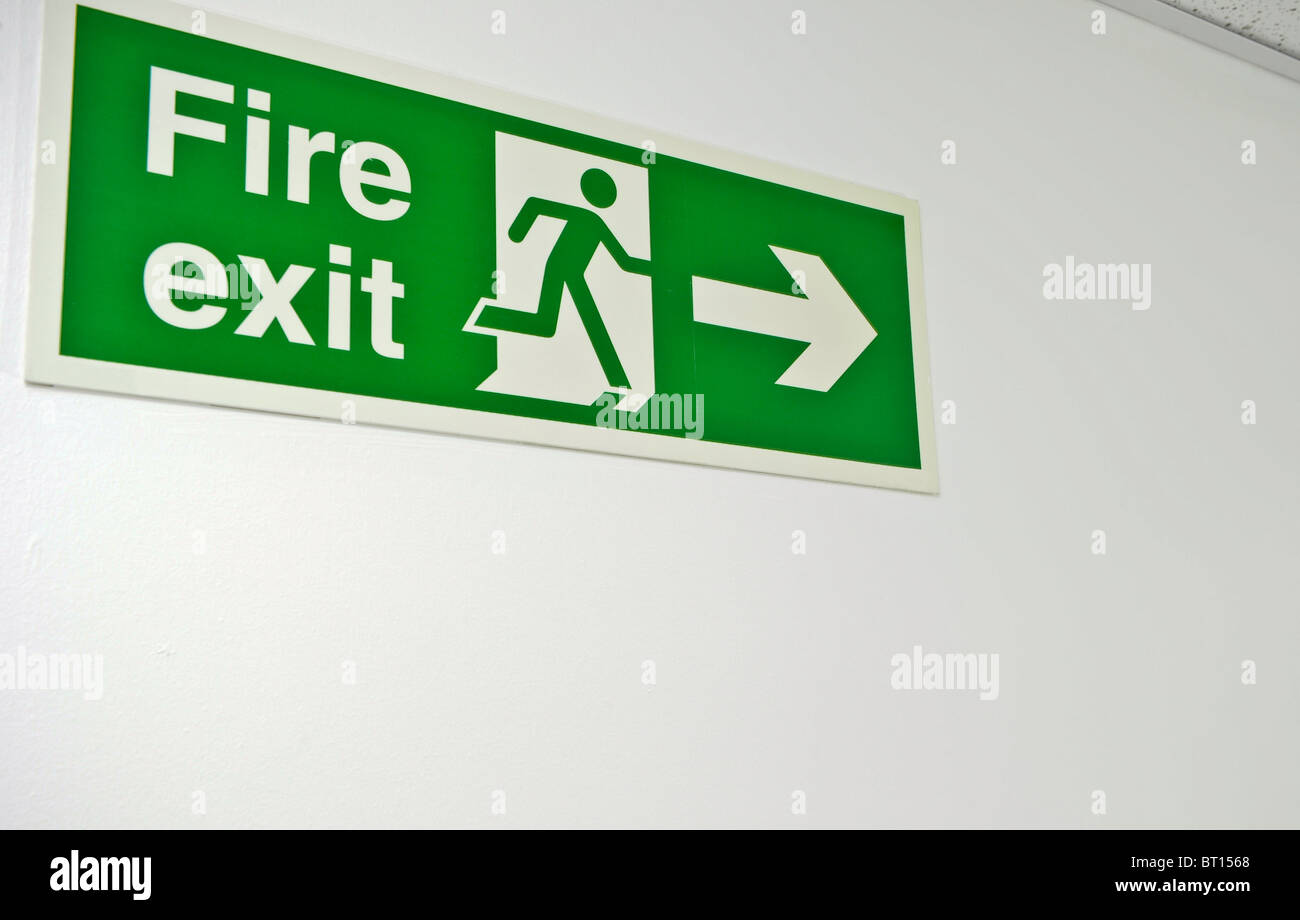 green fire exit sign mounted on wall Stock Photo
