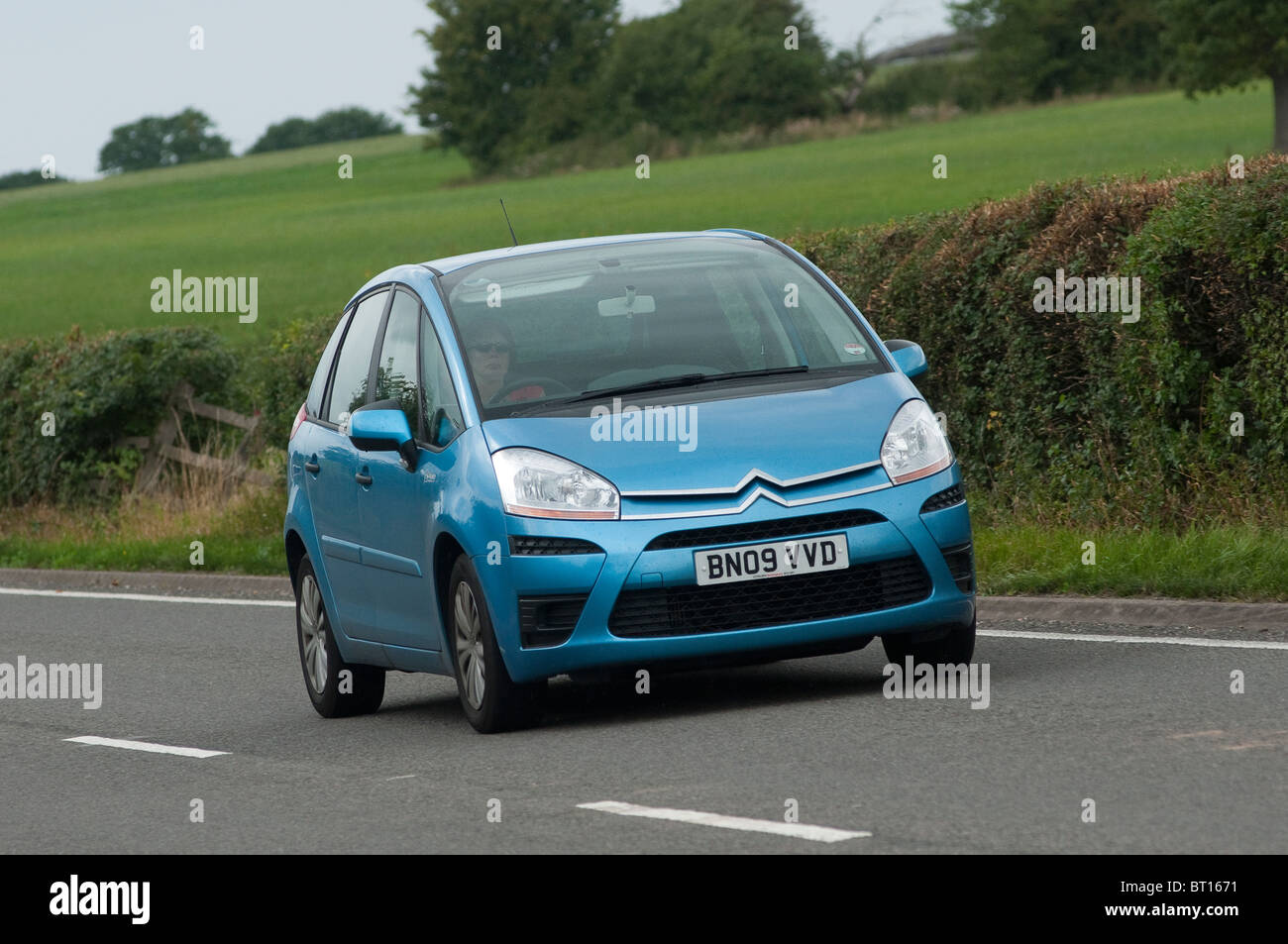 Blue citroen car travelling along a road in the English countryside. Stock Photo