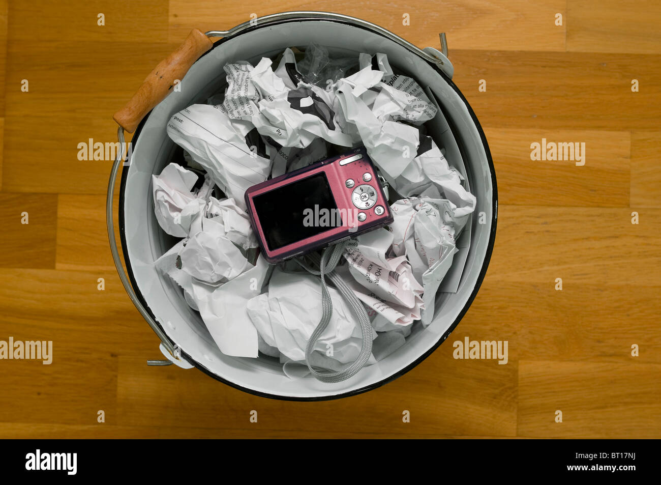 Digital camera thrown in waste paper basket bin Stock Photo