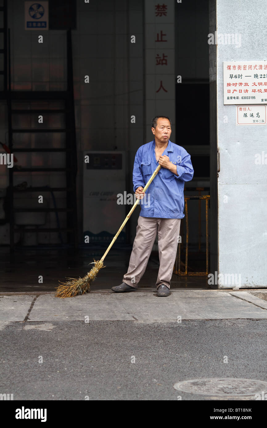 A Chinese worker pause from his duties of sweeping to watch passerbys Stock  Photo - Alamy