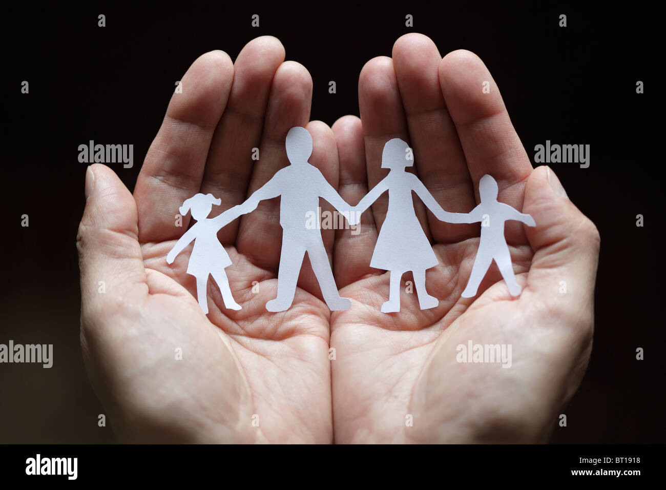 Paper chain family protected in cupped hands Stock Photo