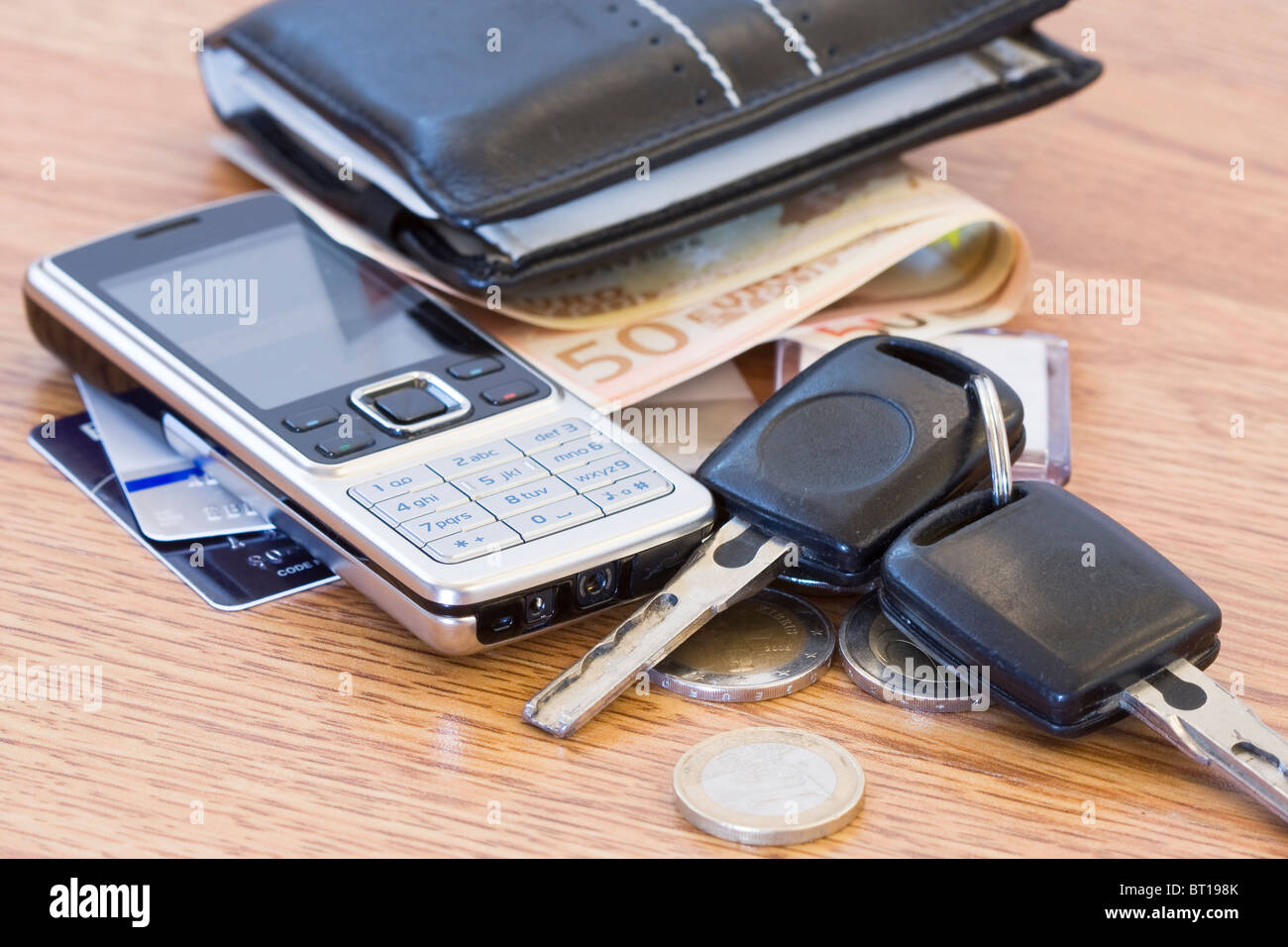 Mans wallet, change phone and car keys on the table Stock Photo