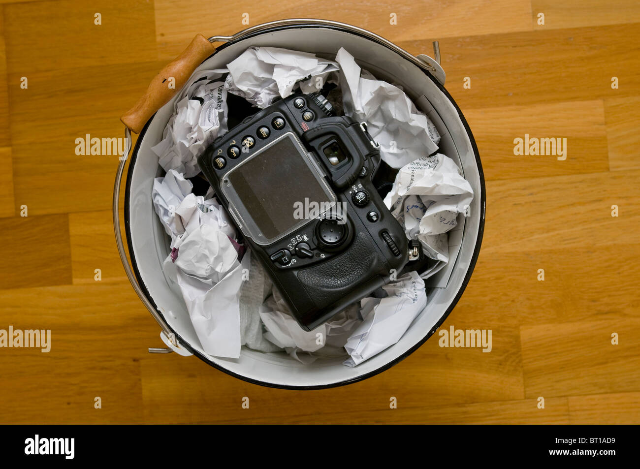 Digital camera thrown in waste paper basket bin Stock Photo