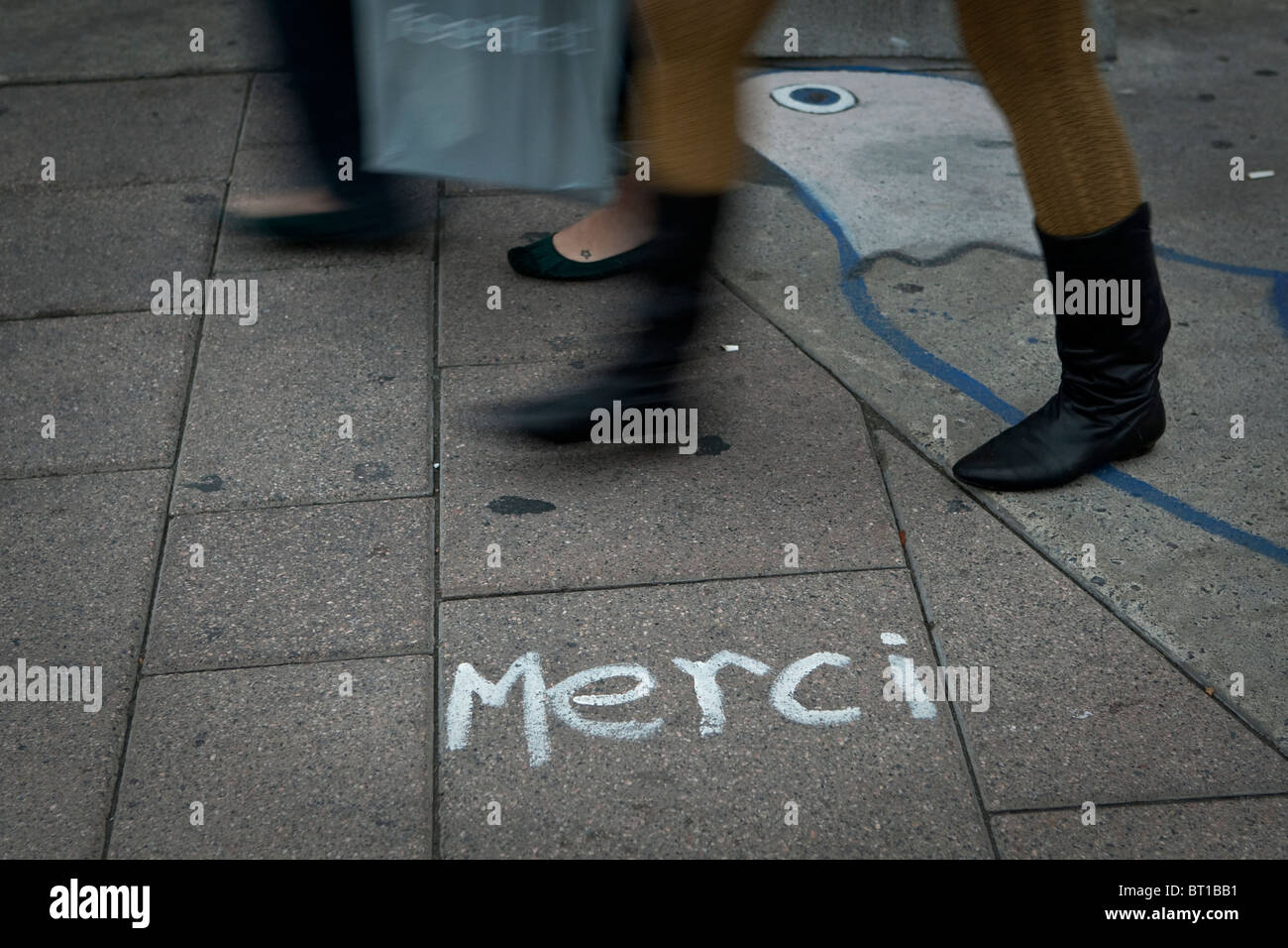Pedestrians walk by a "Merci" graffiti written on a Ottawa sidewalk Saturday September 25, 2010. Stock Photo