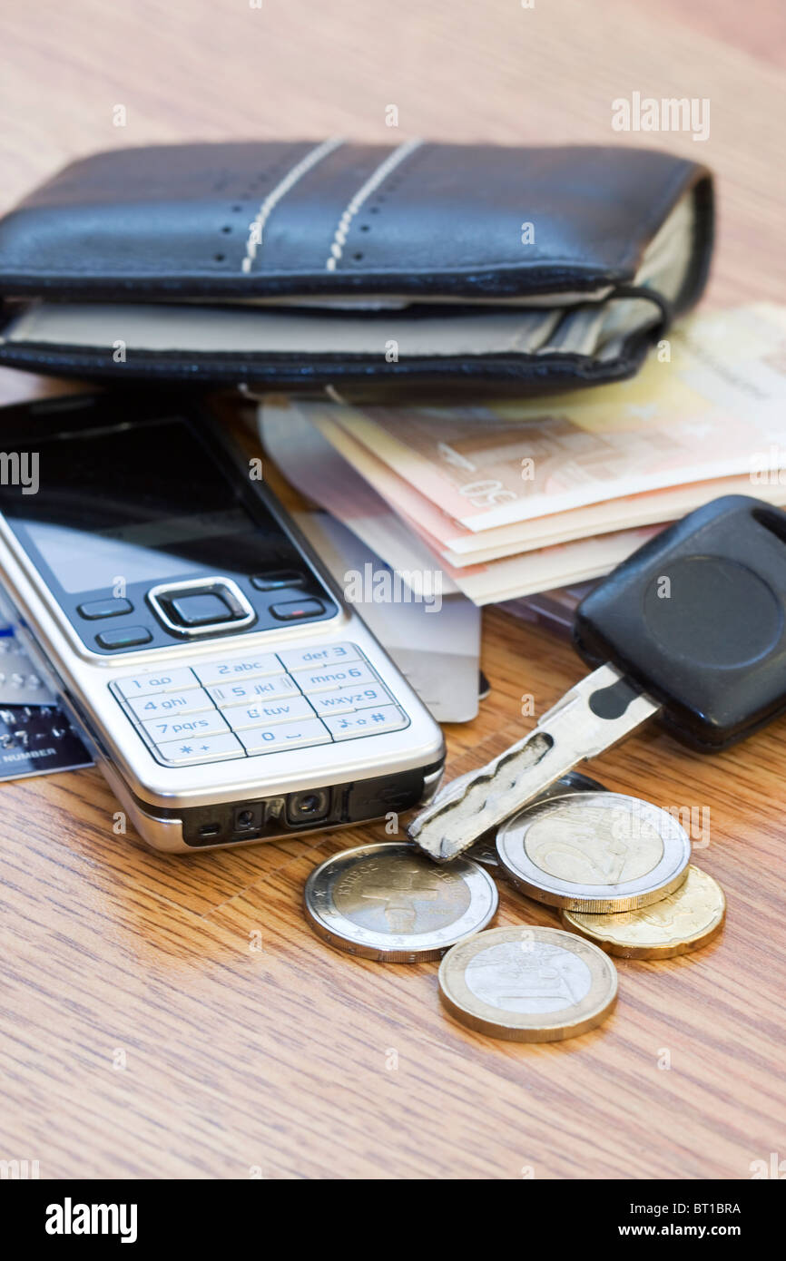 Mans wallet, change phone and car keys on the table Stock Photo