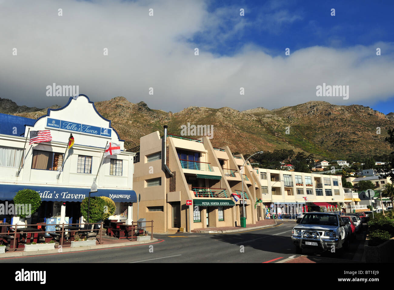Street scene of a restaurant on windy day in Gordons Bay. The mountain and cloud form the backdrop of this colourful setting. Stock Photo