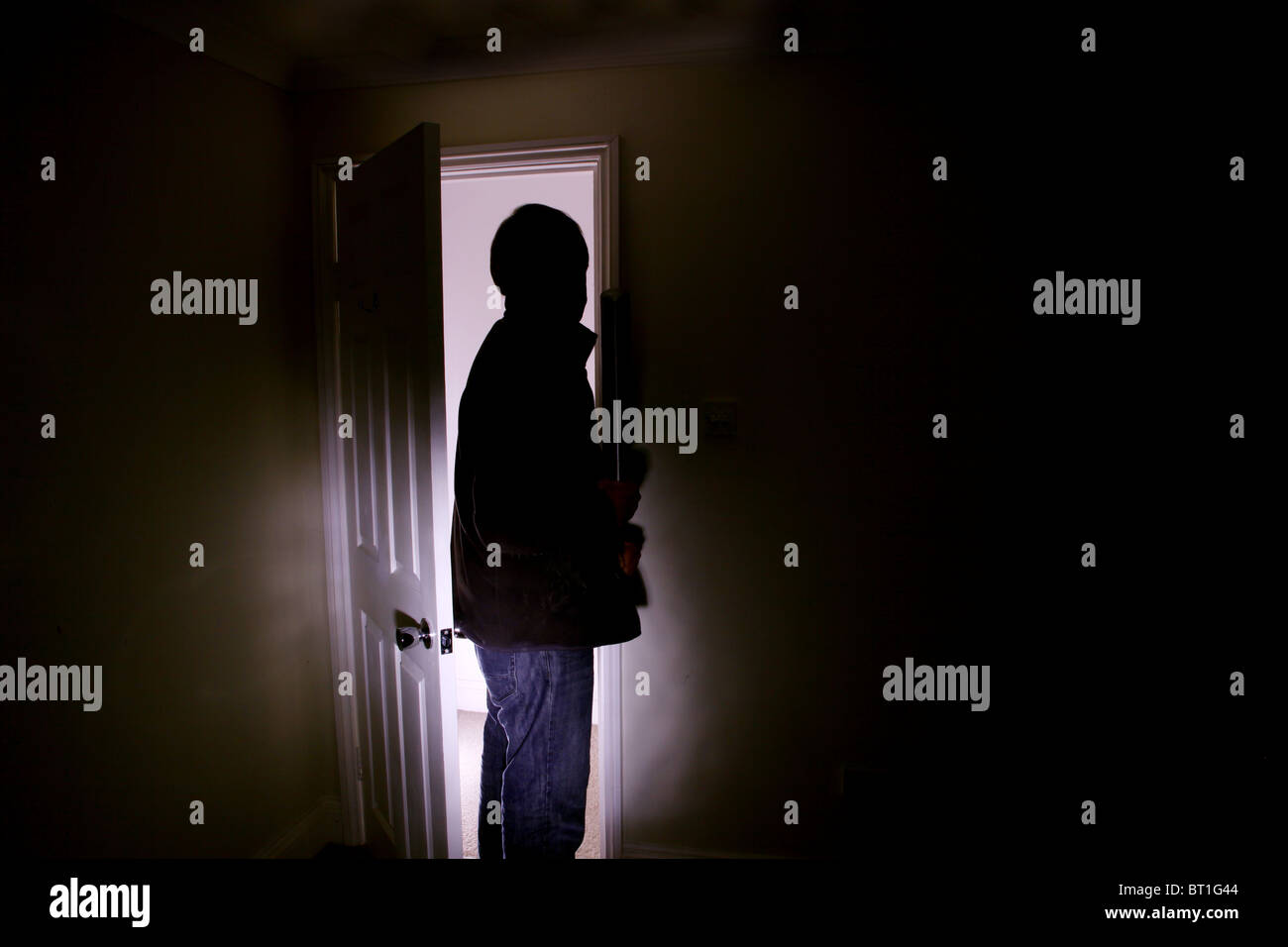 Man standing in the shadows of a dark room Stock Photo