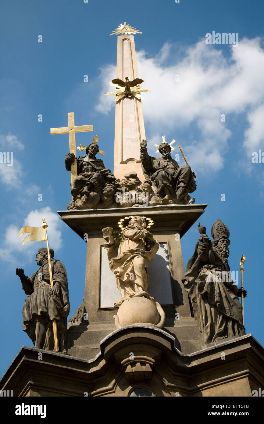 Prague - baroque column of Holy Trinity and tower of st. Vitus cathedral - infront of St Nicolas Church at Lesser Town Square - Stock Photo