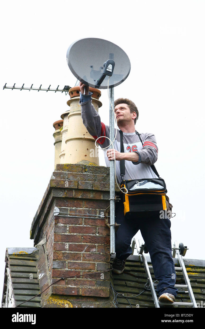 An Aerial and satellite engineer works on a roof top. Picture by James Boardman Stock Photo Alamy