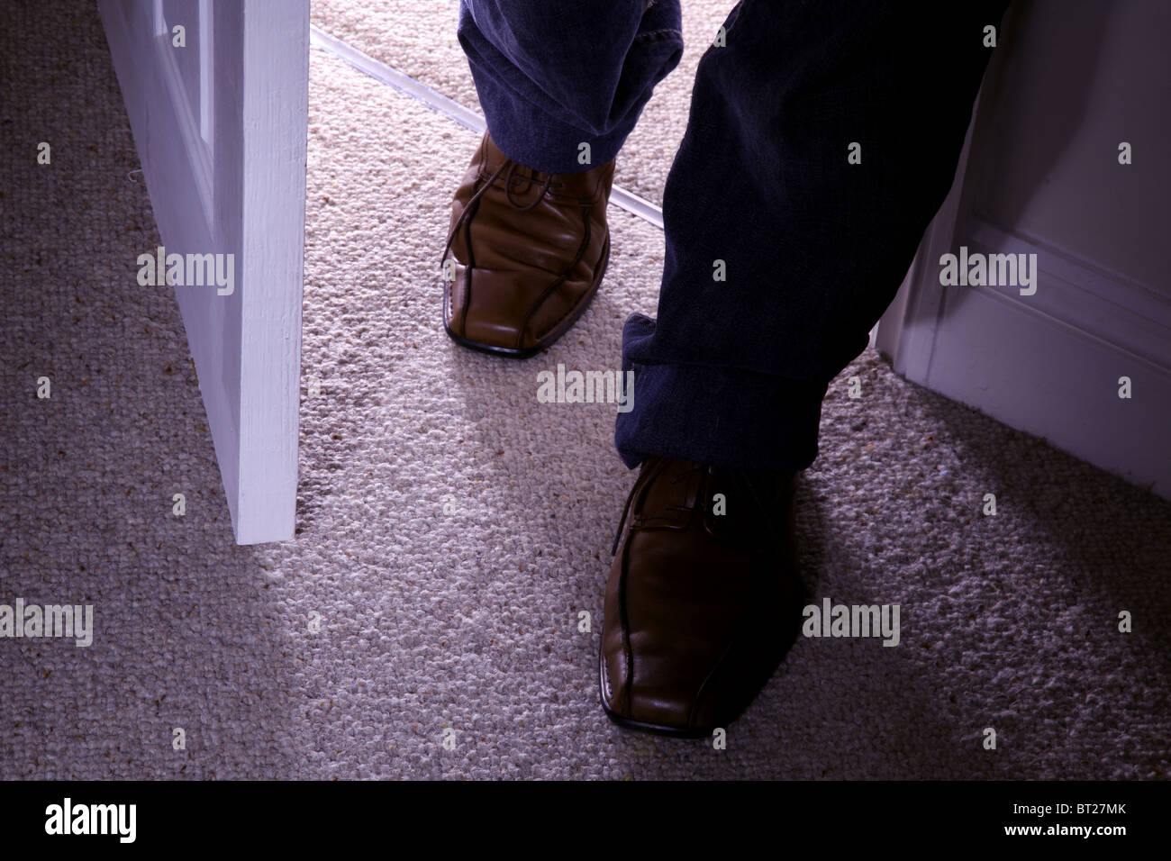 Feet with brown shoes entering a carpeted room Stock Photo