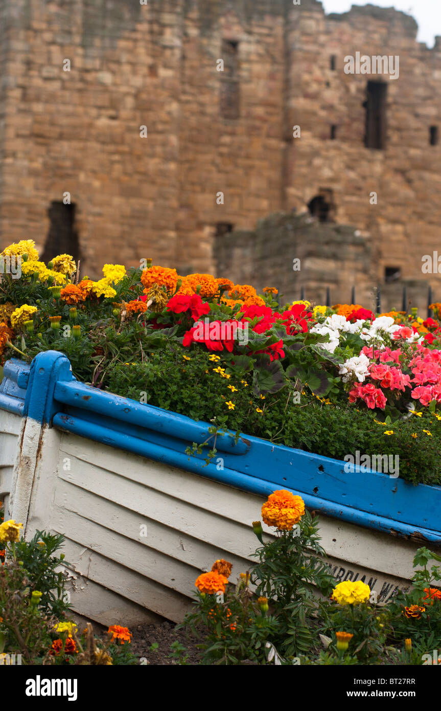 Flowers inside a boat with the ruins of Tynemouth Priory in the background, Tynemouth, Tyne and Wear, England, UK. Stock Photo