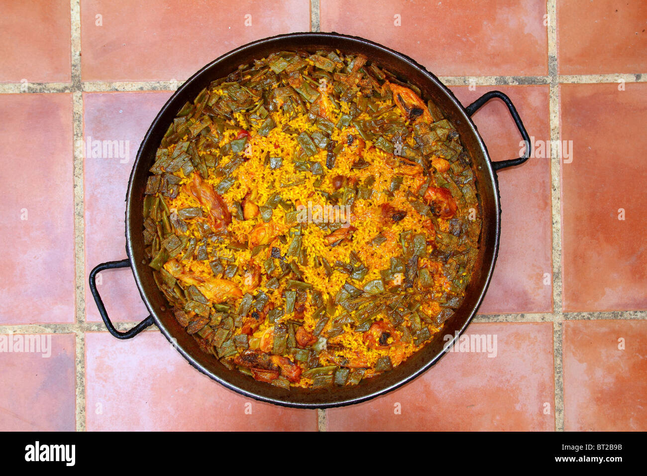 Paella rice recipe Mediterranean Spain round pan on clay floor Stock Photo