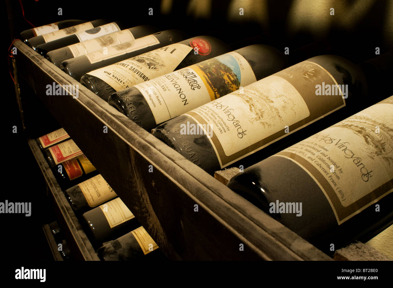 Old vintage dusty wine bottles resting in wine cellar racks Stock Photo