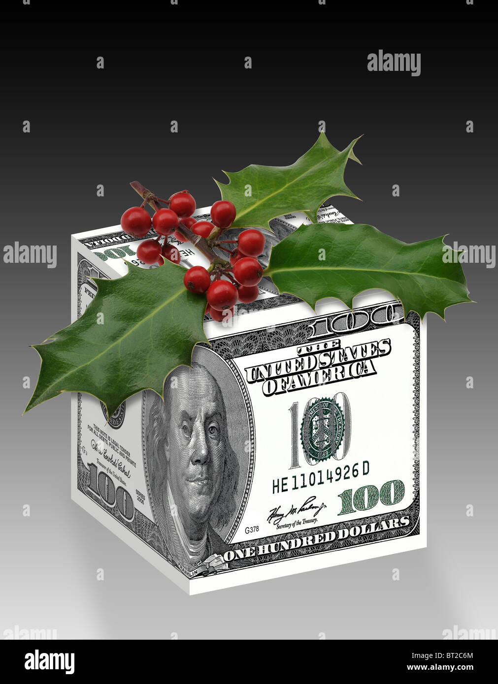 U. S. Dollar money gift box wrapped up with $100 notes with Christmas holly on top. Stock Photo