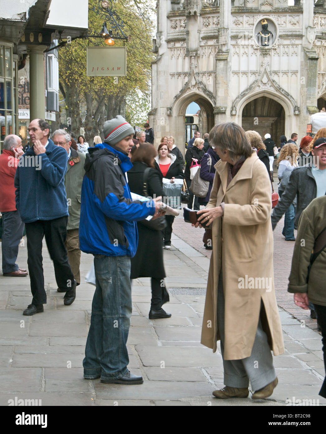 A 'Big Issue' seller in East Street, Chichester, Sussex with shoppers - EDITORIAL USE ONLY Stock Photo