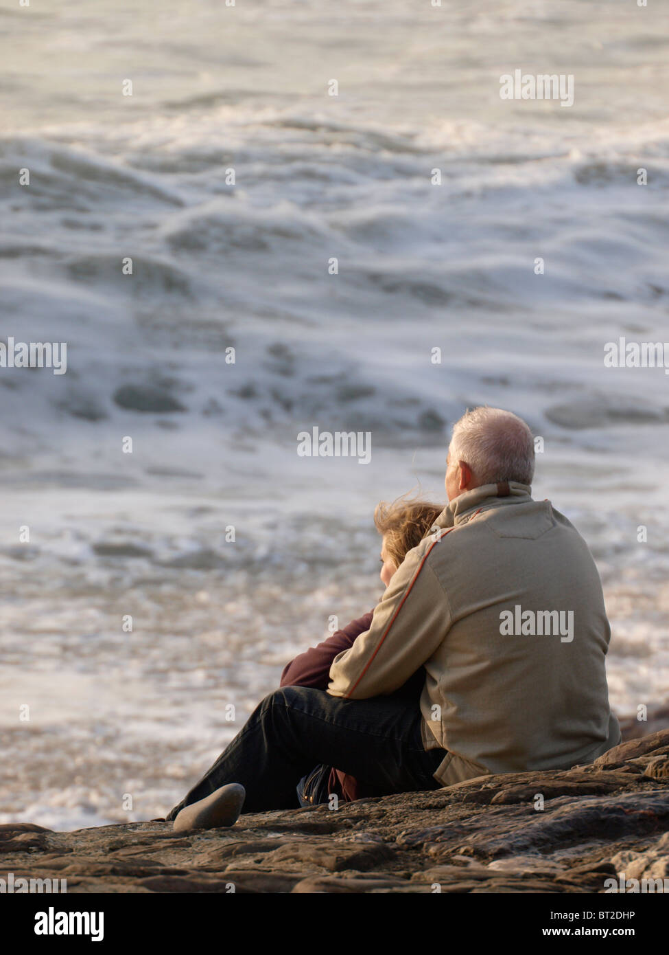 Older couple watching the waves, Bude, Cornwall, UK Stock Photo