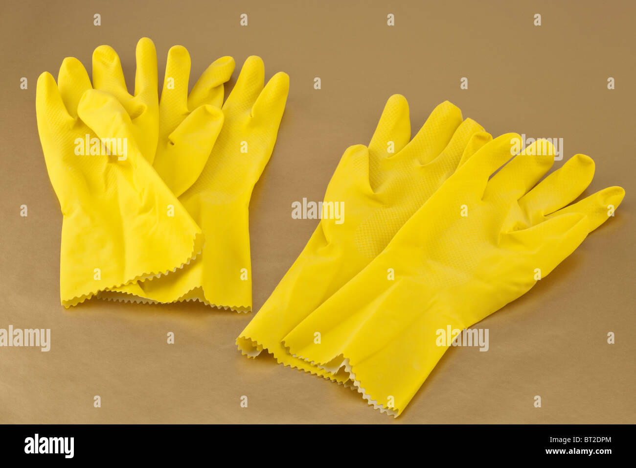 Two pairs of yellow medium sized household rubber gloves Stock Photo