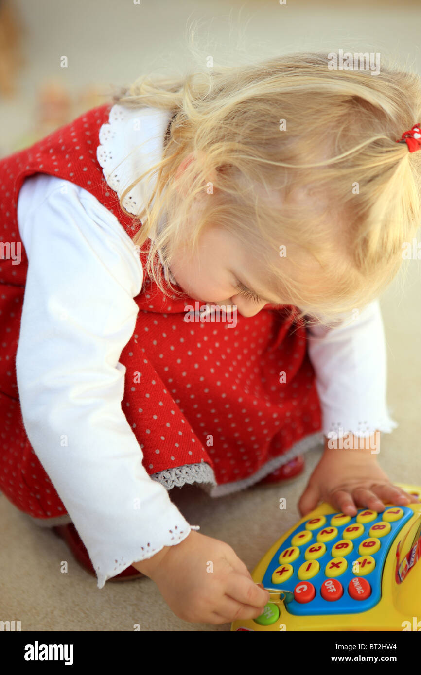 Blond haired 2 year old girl playing with toy cash register Stock Photo