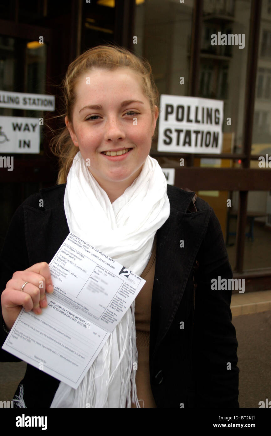 First Time Voter proudly showing voting card outside a polling station Stock Photo